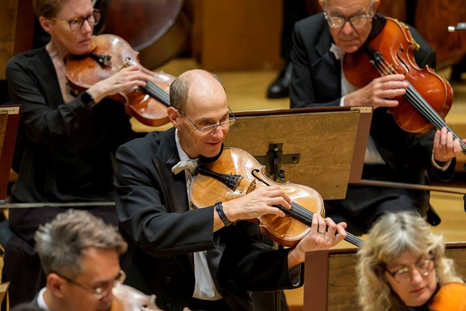 Closeup shot of CSO viola Lawrence Neuman smiling and performing on stage