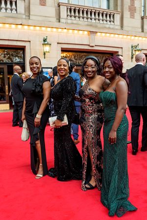 A group shot of Symphony Ball attendees dressed up in gowns on the red carpet