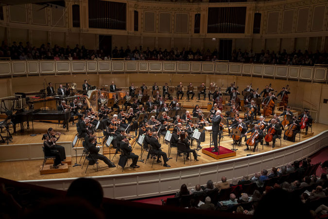 Wide shot of the Orchestra and Hannu Lintu performing on stage