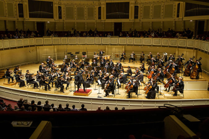 Wide action shot of guest conductor Philippe Jordan leading the CSO on stage