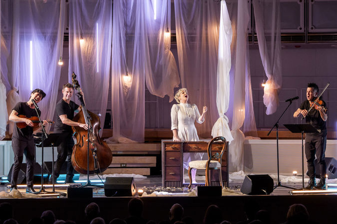 Time For Three sings and plays while Joyce DiDonato delivers a particularly powerful passage from behind a desk in the middle of the stage