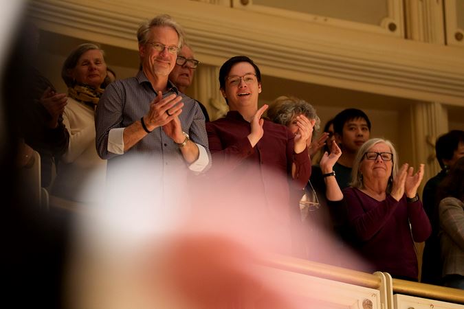 audience members overlooking the stage from the terrace smile and give a standing ovation