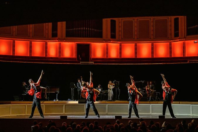 four tango couples strike a pose at the same time, the women in flowing red dresses with one leg in the air and the men stoic in black suits